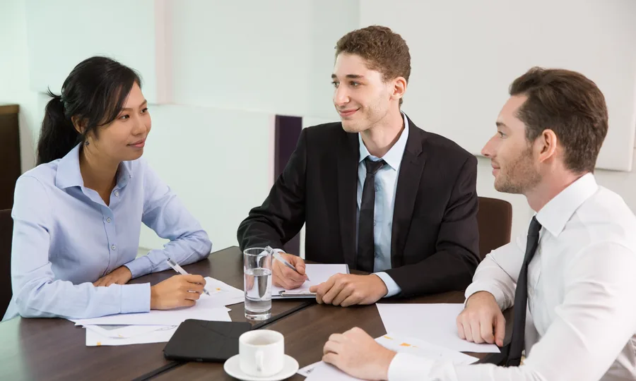 Three colleagues reviewing papers together at a meeting table