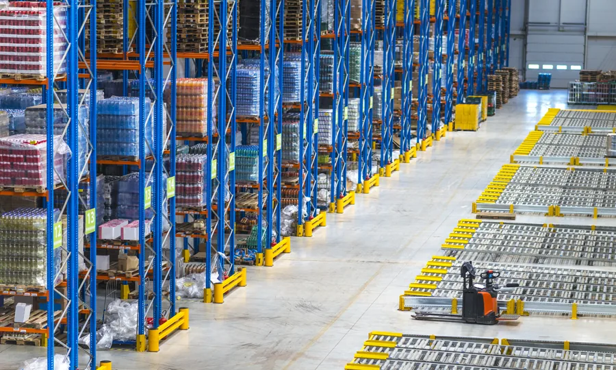 Warehouse aisles lined with tall pallet racks of packaged goods