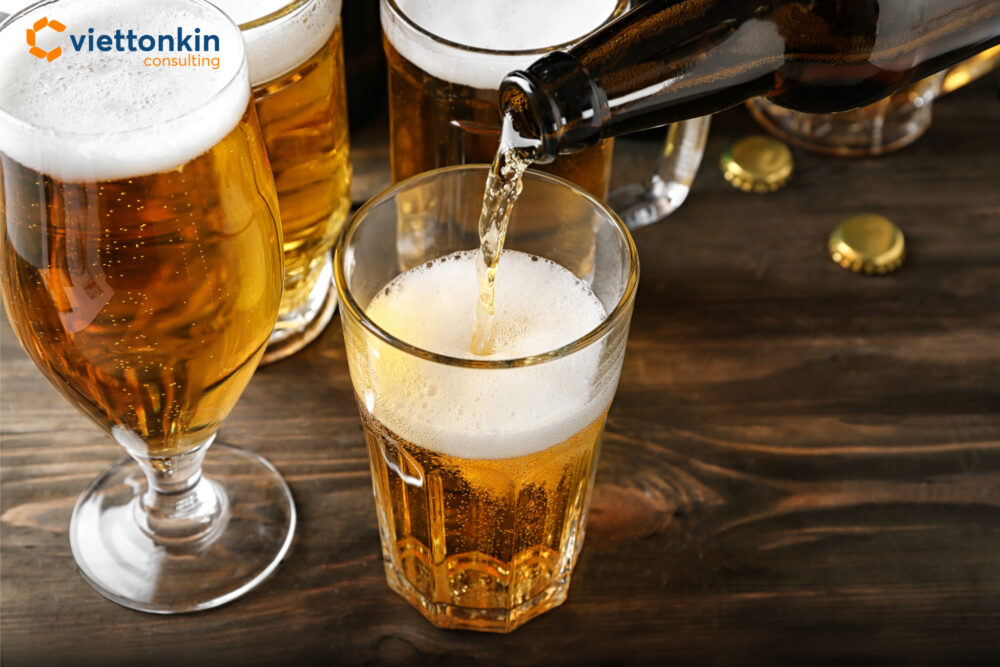 A close up of beer being poured from a bottle into a glass on a wooden table