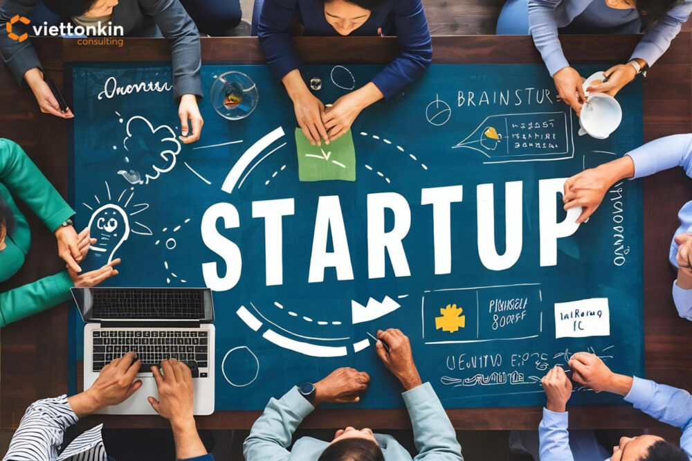 Group of entrepreneurs discussing ideas around a large table with the word ‘STARTUP’ at the center, symbolizing Vietnam’s maturing startup environment and collaborative innovation culture